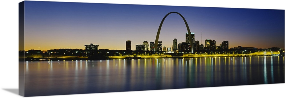 Panoramic photograph of skyline featuring the St. Louis Arch and waterfront at dusk.