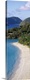 image thumbnail of A tall narrow photograph of a sandy beach lined with palm trees and more islands in the background.