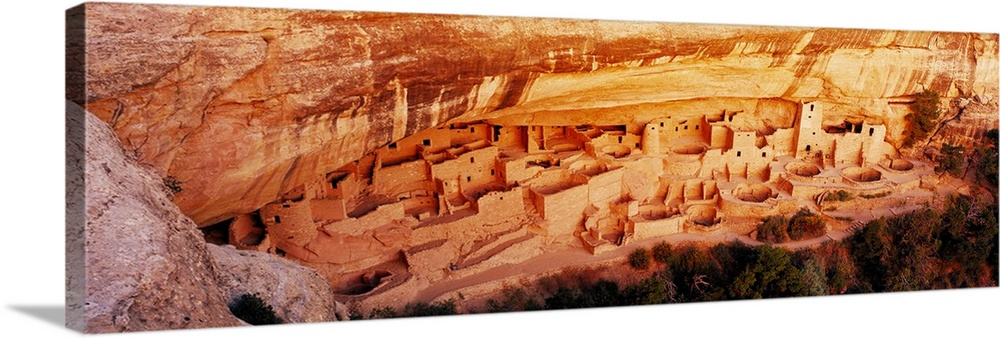 This panoramic vista looks down into the cliff dwellings of the ancient Pueblo people as the stones are illuminated by the...