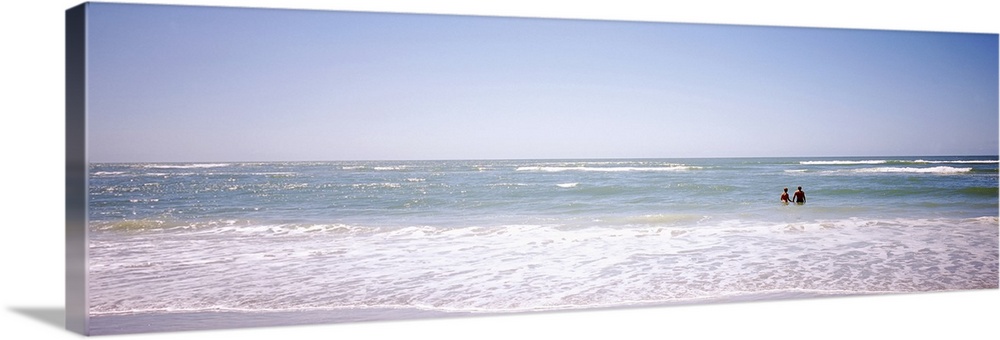 Panoramic image on canvas of the ocean with two people standing in it.