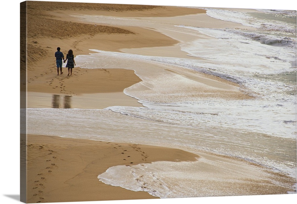 Giant photograph displays two people holding hands and strolling down a sandy shoreline while the crashing waves of the Pa...