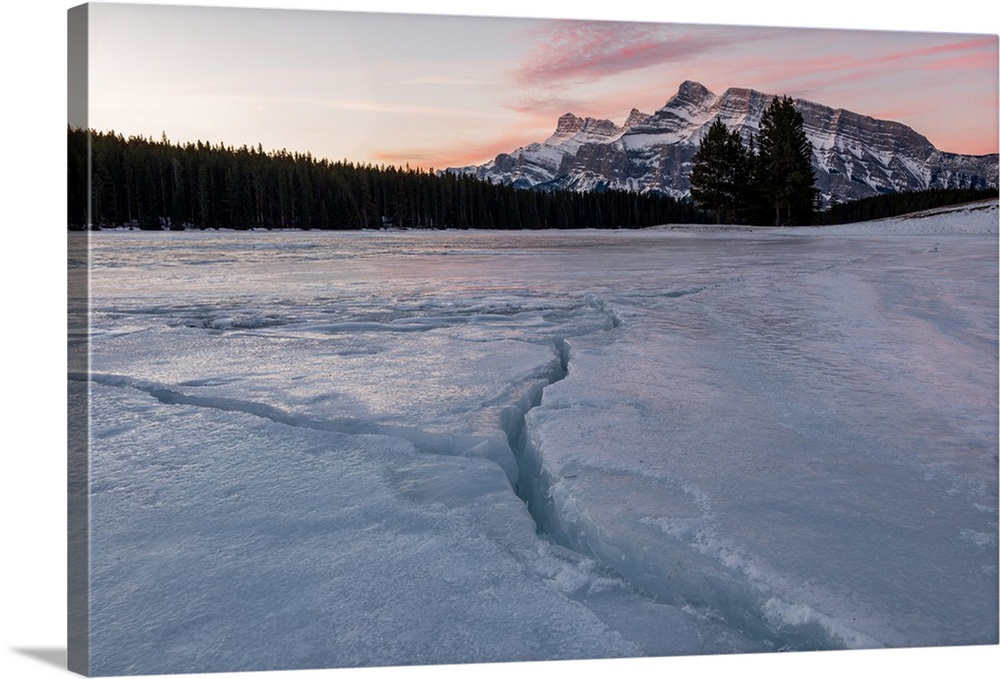 Cracks in ice on frozen lake at sunrise, Mount Rundle, Banff National Park, Alberta, Canada