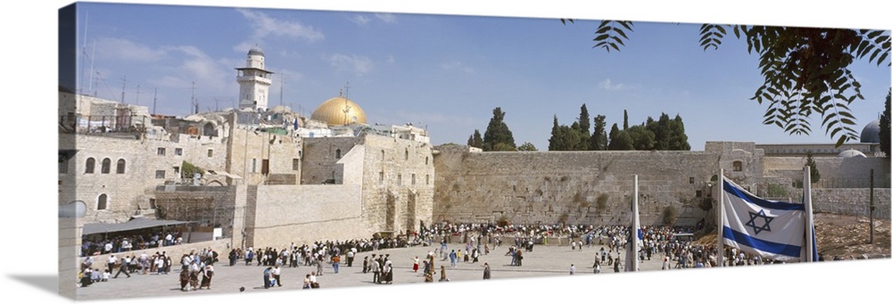 Wide angle photograph of a crowd of people surrounding the Wailing Wall in Jerusalem, Israel, the Dome of the Rock can be ...