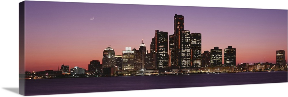 Panoramic photograph of skyline and waterfront lit up at sunset with the moon high in the sky.