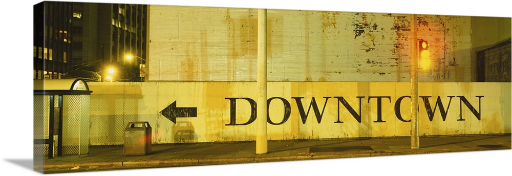 Large panorama of a half wall in downtown San Francisco with a painted sign on it pointing pedestrians towards downtown.