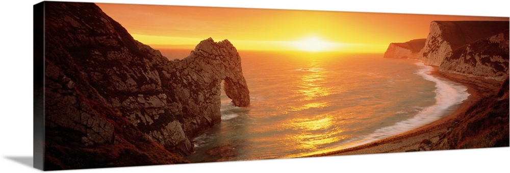 Panoramic, oversized photograph of the limestone arch, Durdle Door, extending into the water along the Jurassic coast as t...