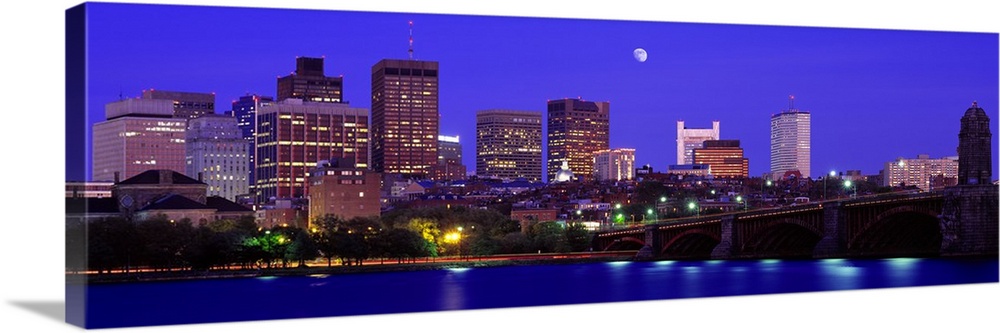 Panoramic canvas of a cityscape on the waterfront with a bridge leading to it and a bright moon in the evening sky.