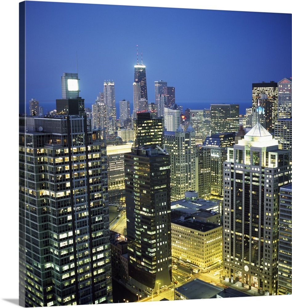 Square photo print of tall buildings in downtown Chicago lit up at night.