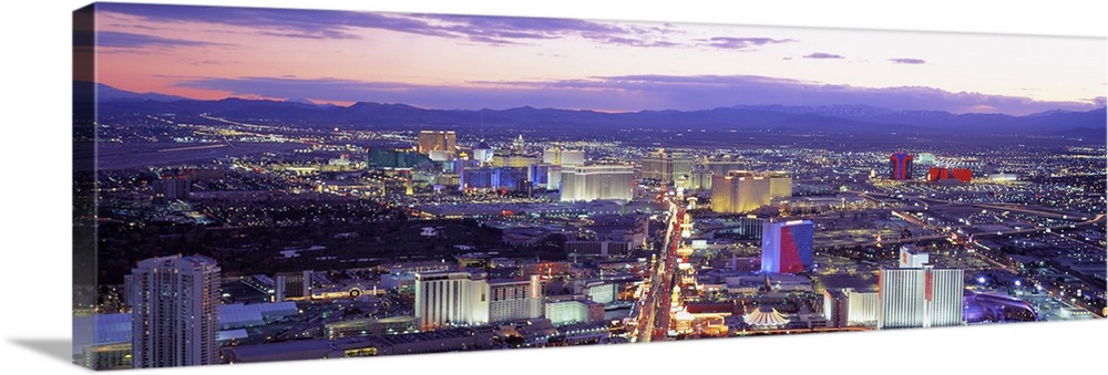 Aerial shot taken over the city of Las Vegas with casinos, buildings and houses in view. All are illuminated under a sunse...