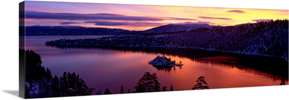 Panoramic photograph of bay at sunset twisting through snow dusted mountains and trees.