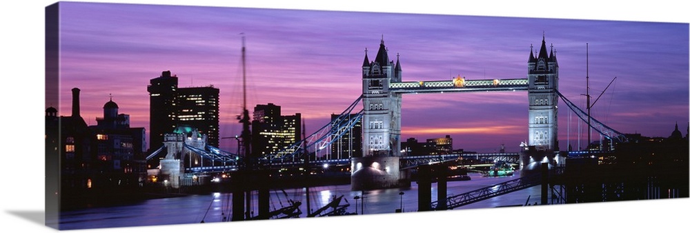 Panoramic view of London's cityscape and the Tower Bridge in front of a pink and purple toned sunset.