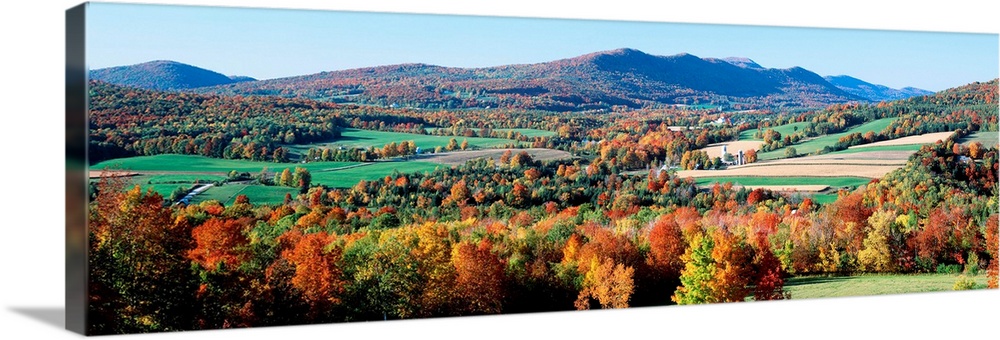 A valley in New England filled with open pastures and accented with trees covered with leaves turning in autumn.