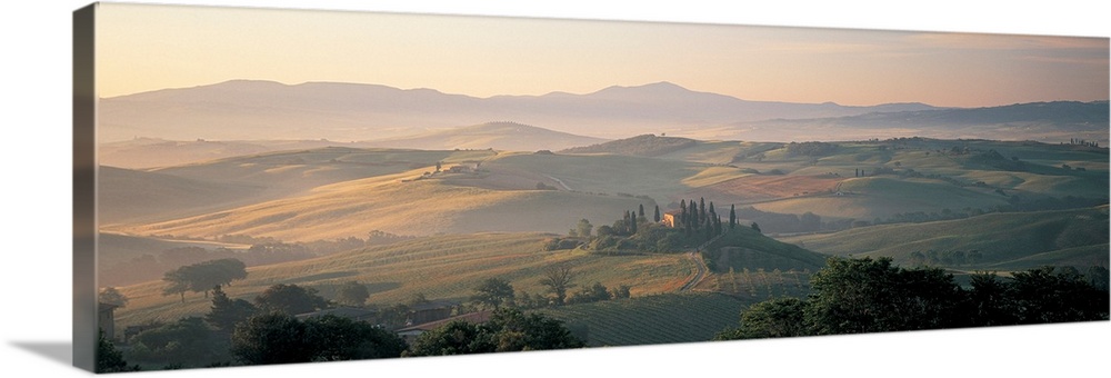 The sun rises over the farmland and hills of the mist covered country side in this panoramic photograph wall art.