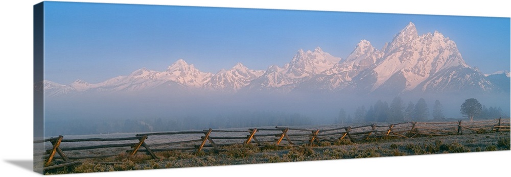 Fence in a field with a mountain range in the background at sunrise, Teton Range, Grand Teton National Park, Wyoming, USA.