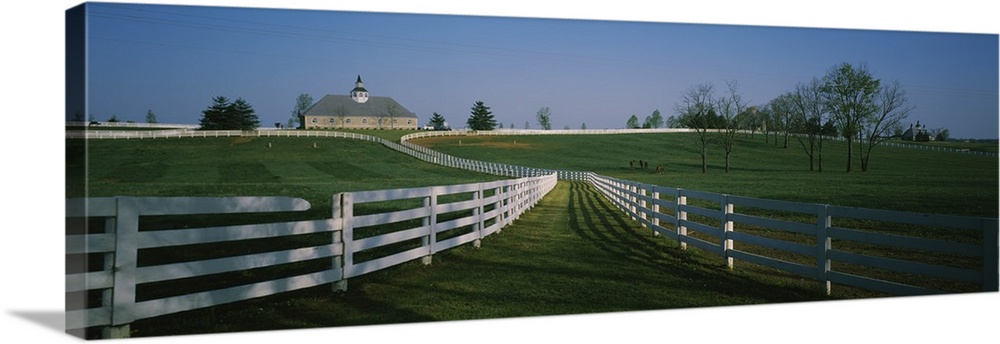 Panoramic photograph of fenced pasture with house in the distance.