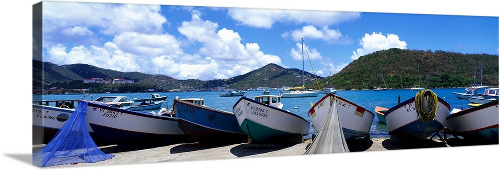 Panoramic photograph taken of boats out of the water. Behind them is the ocean water and the tall cliffs in St. Thomas.