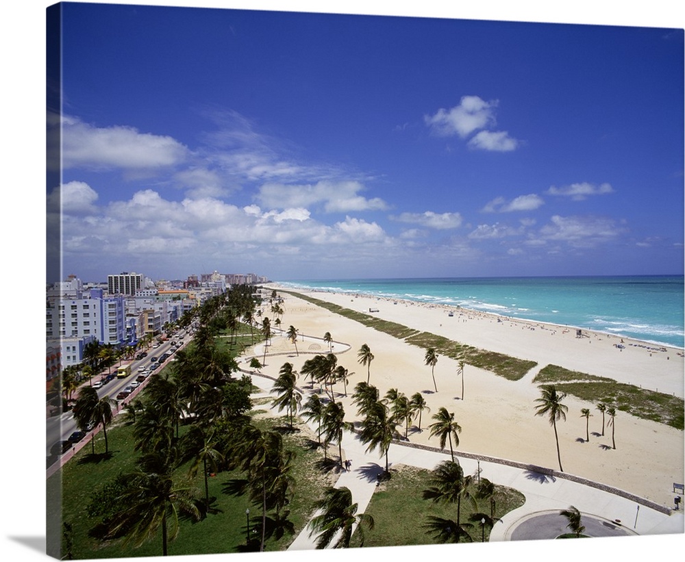Canvas photo art of a city and street on the left meeting white sand and ocean on the right with palm trees sprinkled thro...
