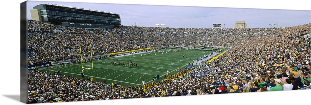 Wide angle photograph of Notre Dame Stadium, full of fans during a football game, in South Bend, Indiana.