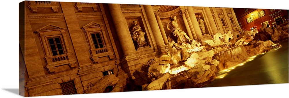 Panoramic canvas photo of Roman statues that are bathed in light at night.