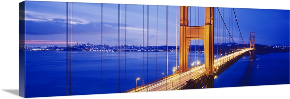 Long and narrow photo print of an up close view of the Golden Gate Bridge lit up at night with cars driving across it.