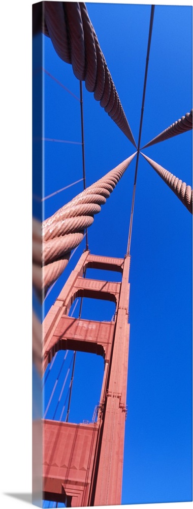 Up-close vertical panoramic photograph of bridge spire and cables under a clear sky.