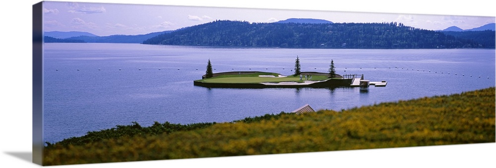 Panoramic photo on canvas of a golf course on a small island in the middle of a lake with mountains in the distance.