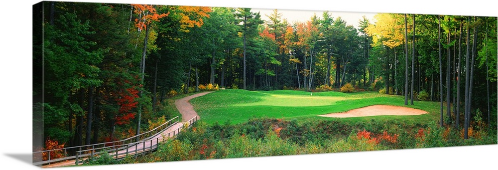 Panoramic photo of a golf green in the Northern United States. A wooden bridge leads to the hole and sand trap which are s...