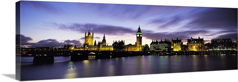Wide angle, nighttime photograph of the London skyline, including Big Ben and Houses of Parliament, reflecting in the wate...