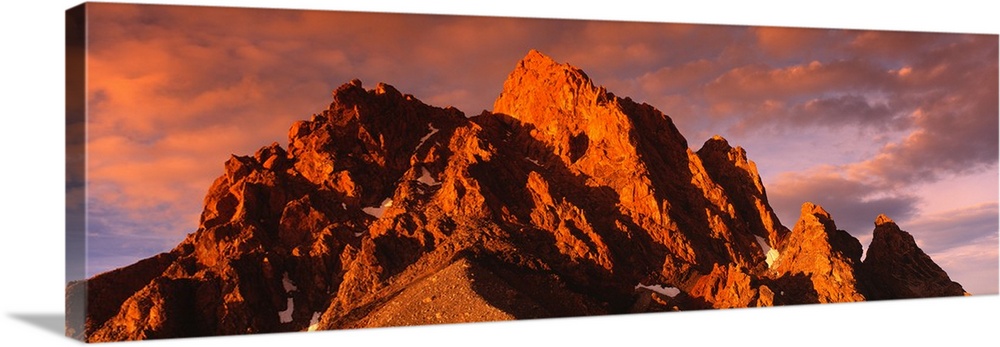 Panoramic photograph of huge rock formation under a cloudy sky at dusk.