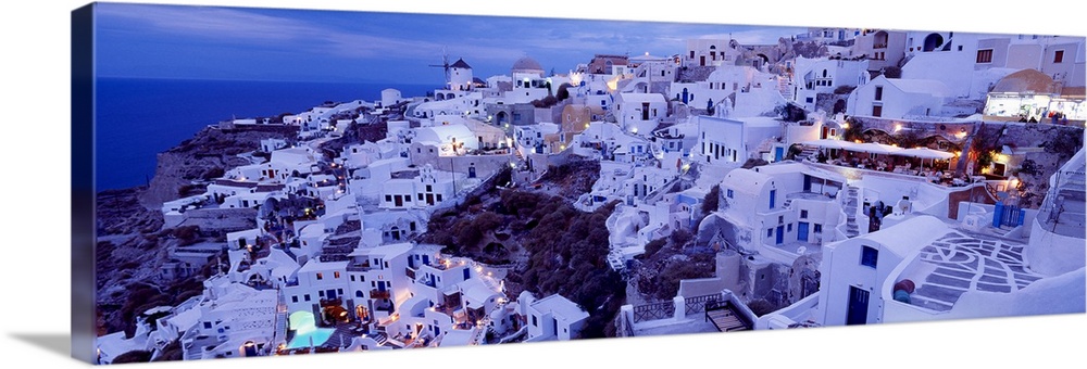 Long horizontal image on canvas of a city on the side of a mountain overlooking the ocean in Greece.
