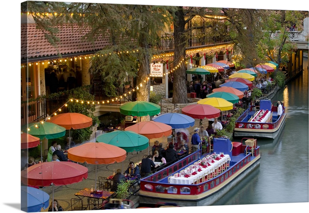 Large photo on canvas of colored umbrellas along a waterfront with boats with tables and chairs docked next to them.
