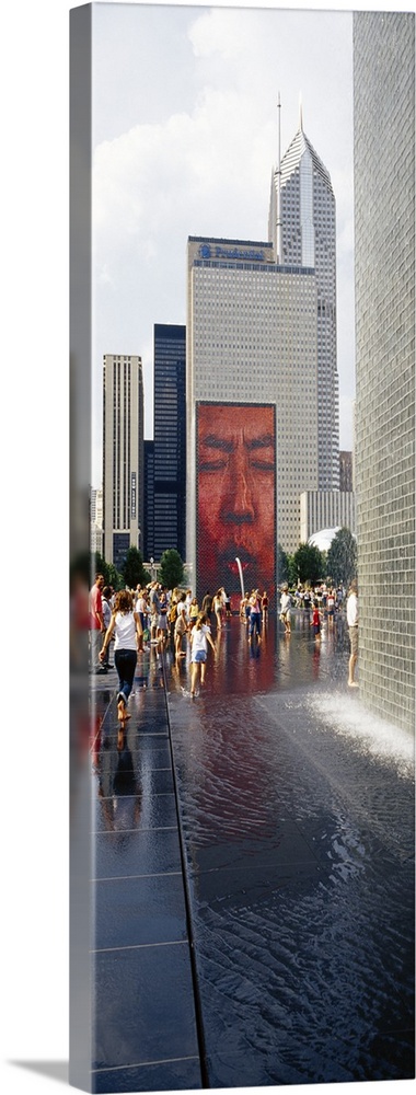 Oversized vertical photograph of a large group of people surrounding Crown Fountain in Chicago's Millennium Park during th...