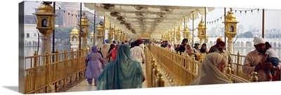 Group of people walking on a bridge over a pond Golden Temple Amritsar Punjab India