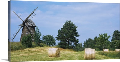 Hay bale in a field with a traditional windmill in the background, Riddarfjarden, Narke, Sweden