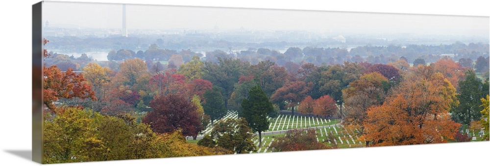 An ariel photograph of Arlington National Cemetery surrounded by autumn colored trees and a view of the Washington monumen...