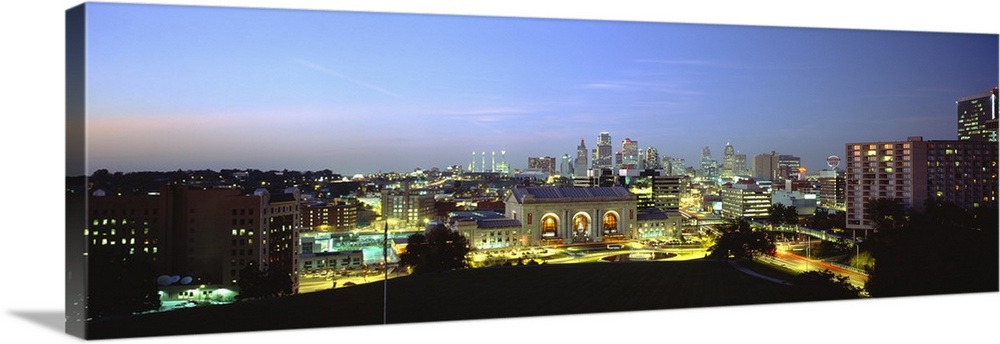 Large panoramic image of a downtown cityscape in Missouri lit up at night.