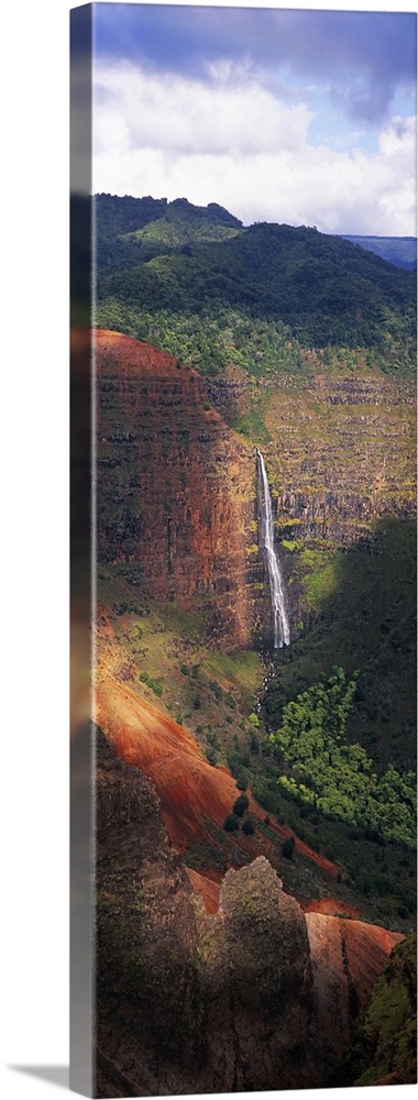 Tall photo on canvas of a waterfall flowing off of a giant cliff seen from a distance.