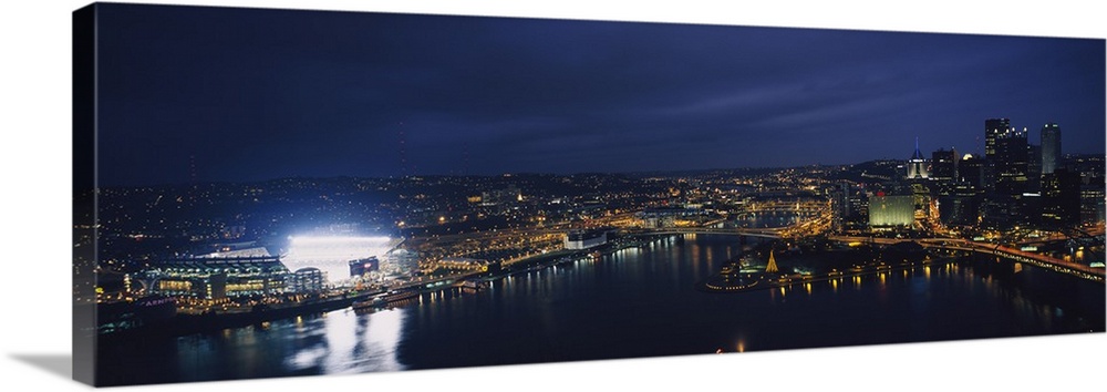 Panoramic photograph of skyline  and waterfront at dusk with building lights on.