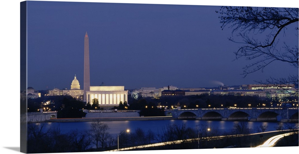 Wall art of major illuminated DC landmarks layered in the distance of a waterfront that a bridge passes over at dusk.