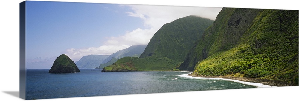 Wide angle photograph taken of immense cliffs that line the coast of a Hawaiian island.