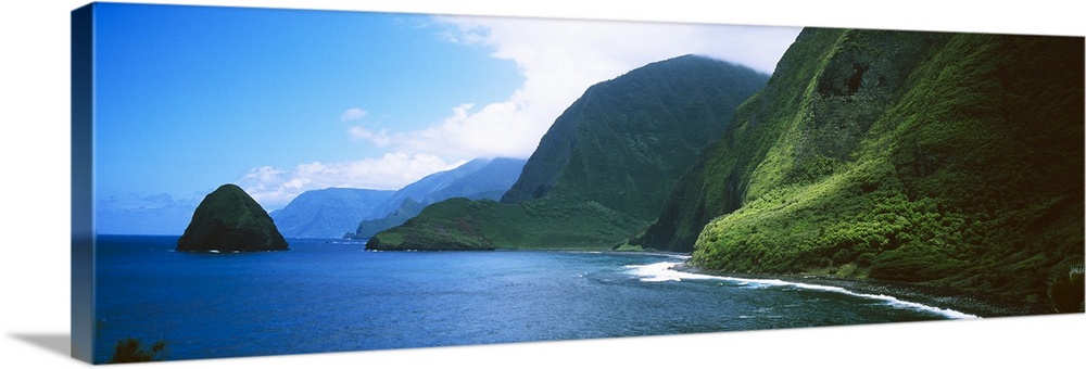 Panoramic photo of large tropical mountains meeting the ocean with a small mountain off shore.