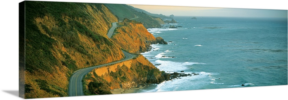 Giant, landscape, panoramic photograph of Highway 1 curving through a cliffside near the shoreline in Big Sur, California.