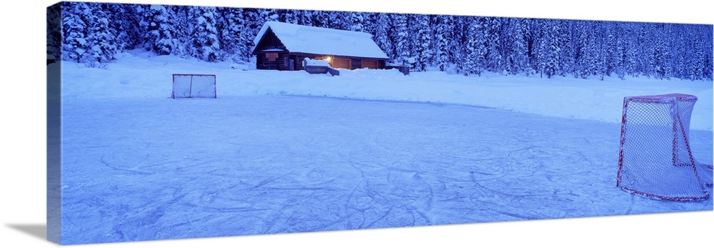 Wall art for the home or cabin this panoramic photograph shows a cabin buried in snow next to a frozen pond covered with t...