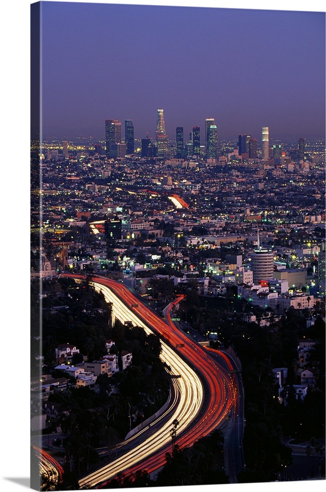 Vertical panoramic of highway running through busy west coast metropolis with city skyline in distance at dusk.  The highw...