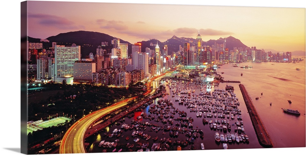 Large photograph of a harbor in Hong Kong at sunset. Hundreds of boats and many buildings can be seen.