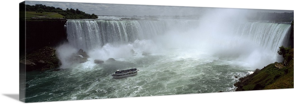 Panoramic photograph of a section of the Niagara waterfall on the border of New York State and Canada, with a small ferry ...