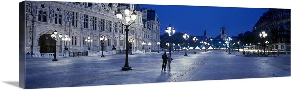Panoramic image of a street outside the Hotel de Ville lit up at night in Paris, France.