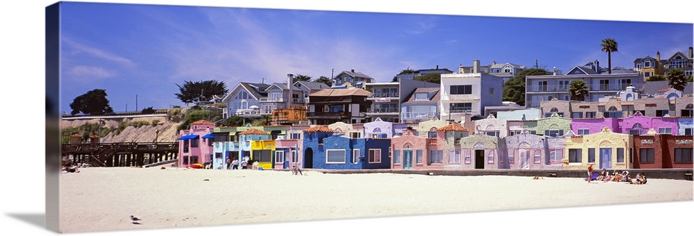Colorful buildings along a sandy boardwalk overlooking the water.