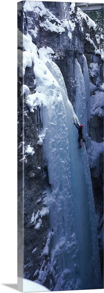 Vertical panoramic photograph of climber on ice covered rock.