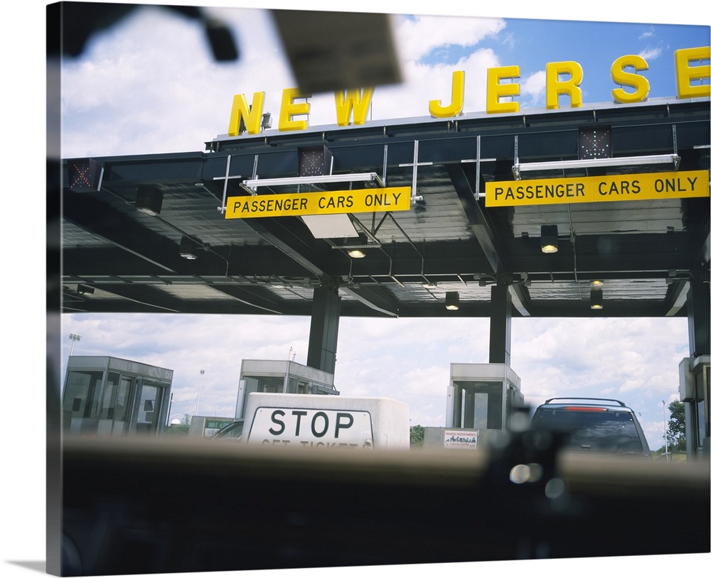 Horizontal, large photograph taken through a car windshield of an information board at a New Jersey toll station.